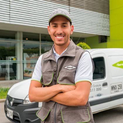 Técnico de servicio Haceb con uniforme verde junto a su vehículo de servicio