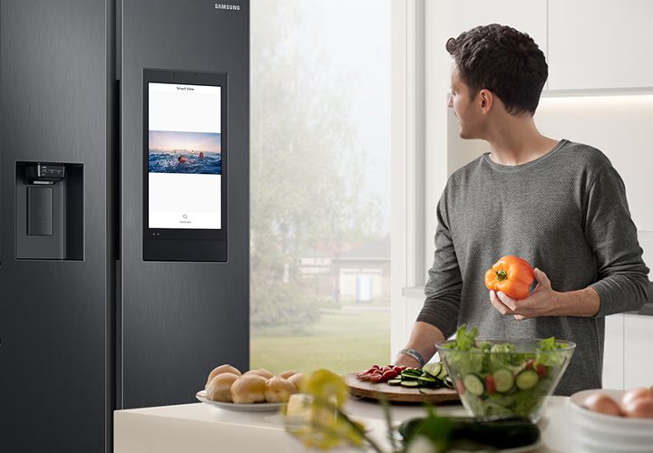 Cliente consultando la pantalla Smart View de su nevera Samsung mientras cocina