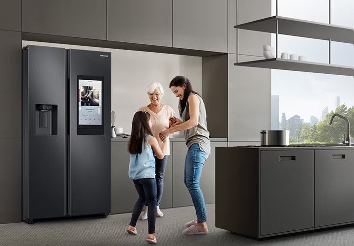 Familia sonriendo junto a su nevera Samsung Family Hub en la cocina de su casa